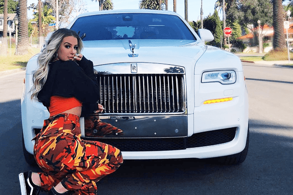 tana sitting in front of her white rolls royce 