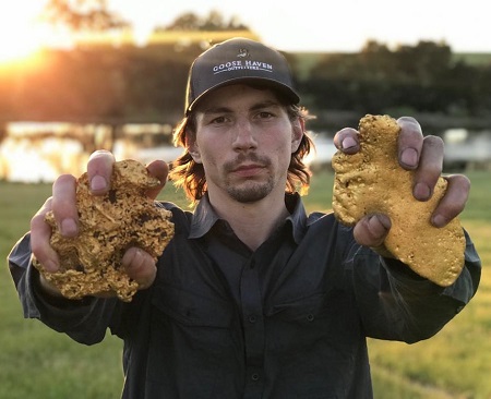 Parker Schnabel holding two fistful of gold nuggests, one in each hand.