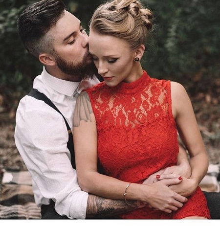 Taylor McKinney kissing wife Maci Bookout on her forehead from behind.