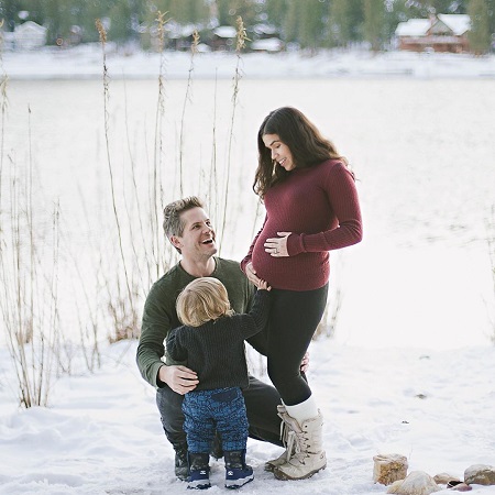 America Ferrera standing pregnant with husband Ryan Piers Williams and son, Sebastian.