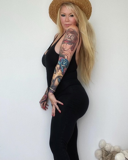 Jenna Jameson in a black skin-tight dress with a hat on.