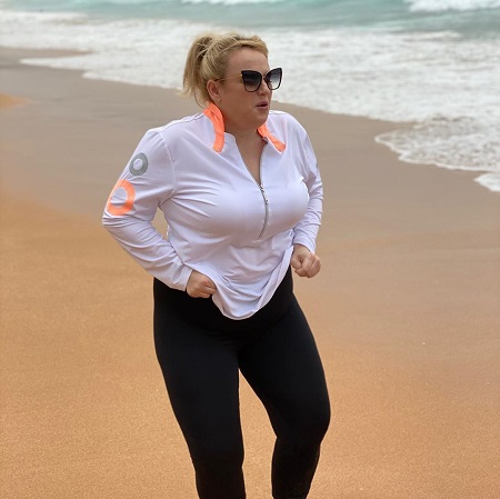 Rebel Wilson in her training suit on the beach.