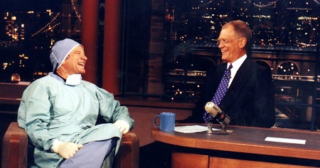 David Letterman, right, talks with comedian Robin Williams on the "Late Show with David Letterman" during the show's taping Friday, Feb. 18, 2000, in New York. Williams donned surgical garb to welcome back Letterman.