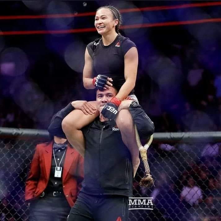 Joshua Gomez carrying his wife Michelle Waterson on shoulder after a match.