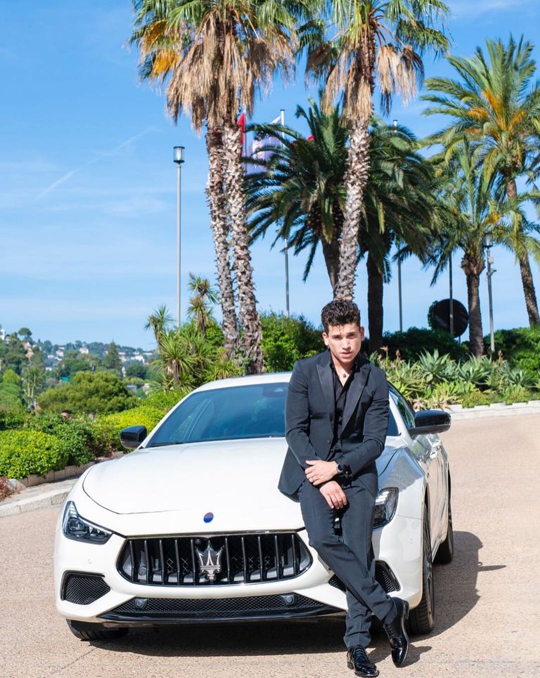 Jaime Lorente posing in front of his car.